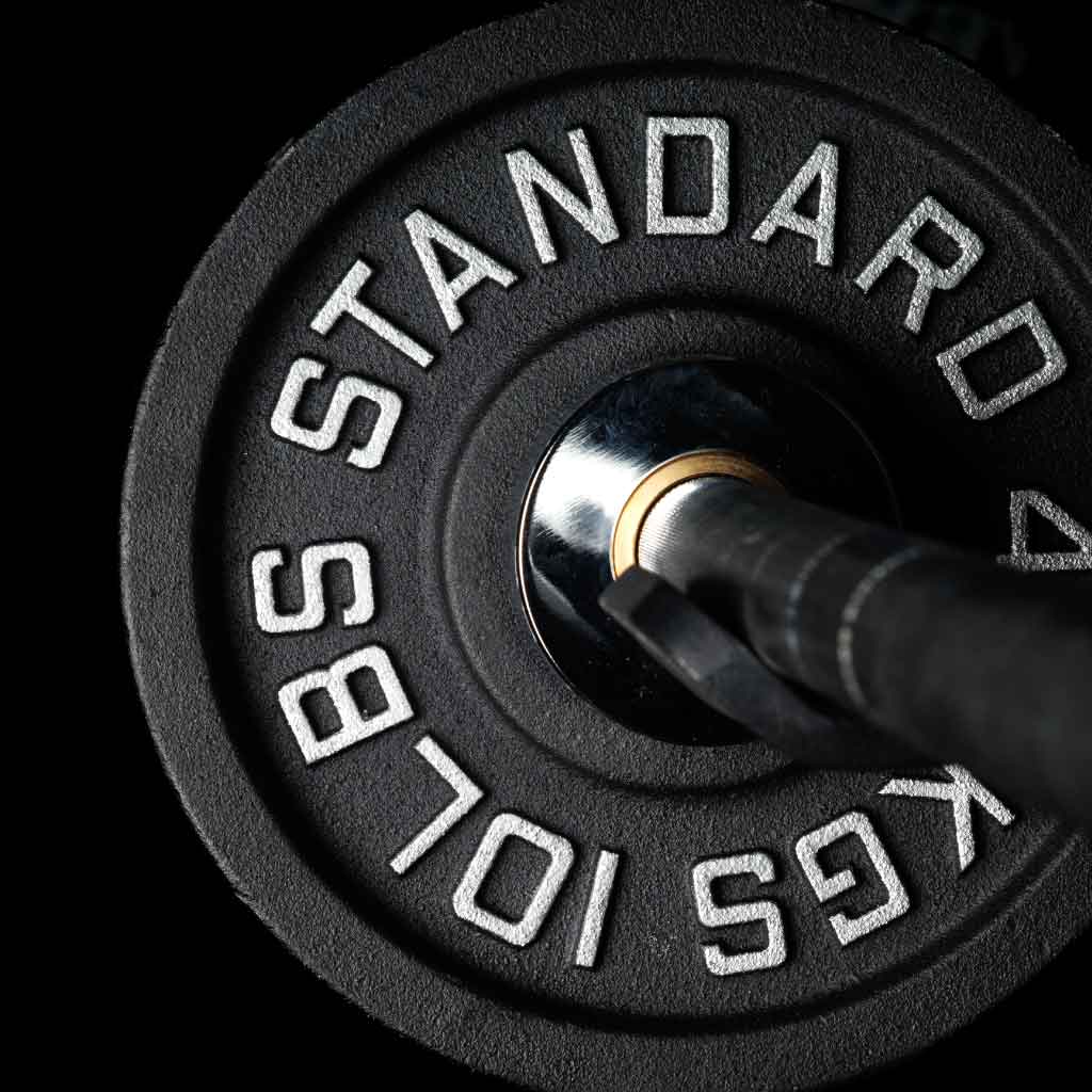 Barbell Standard 10 lb iron weight plate mounted on Olympic barbell sleeve with chrome bushing in gym setting