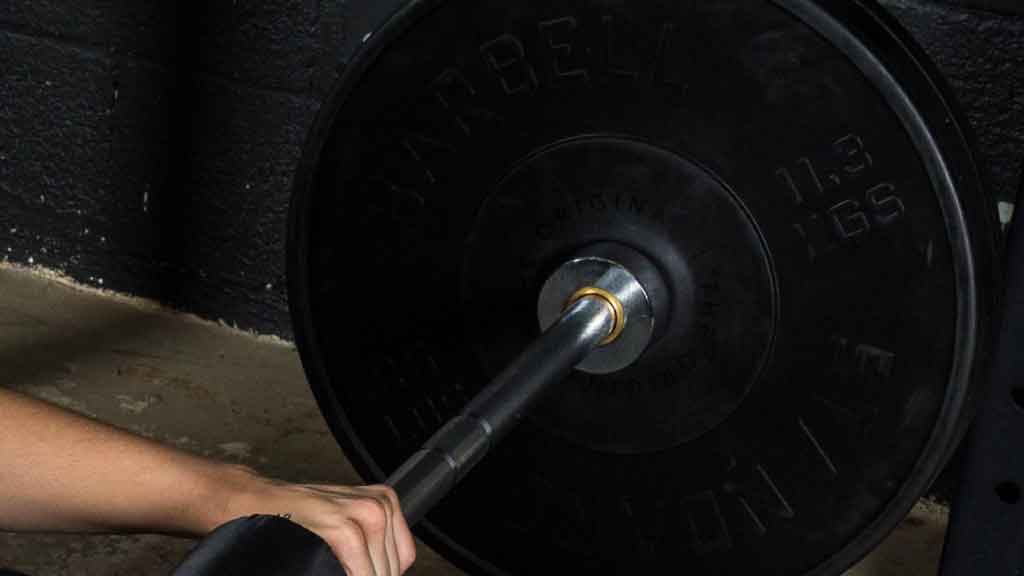 Barbell Standard 1000 training barbell sleeve with bronze bushing loaded with 25 lb bumper plate in use