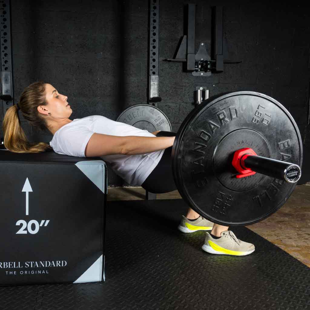 Athlete performing hip thrust with Barbell Standard 1000 barbell and bumper plates on 20 inch plyo box