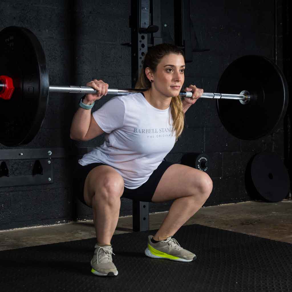 Athlete performing squat with Barbell Standard 1000 barbell and bumper plates in home gym setup