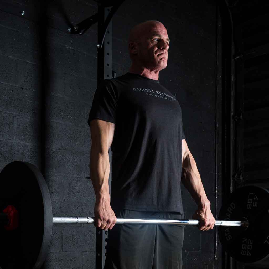 Man in Barbell Standard shirt completing deadlift with 1500 lb barbell in gym.