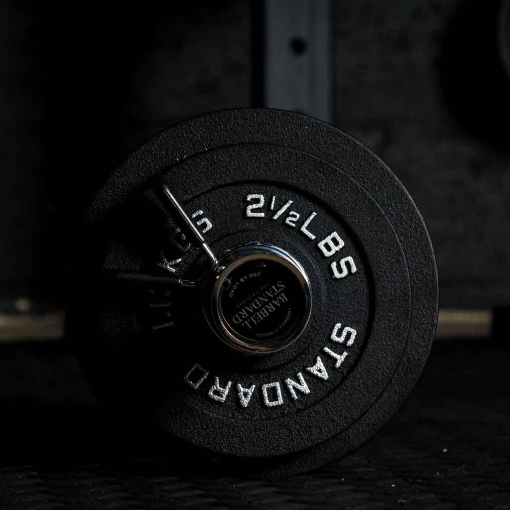 Barbell Standard 2.5 lb iron weight plate stacked on Olympic barbell sleeve with chrome spring collar in home gym