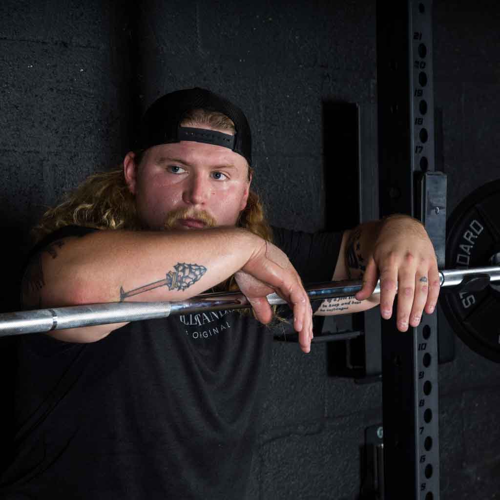 Man resting on Barbell Standard Olympic barbell racked with weight plates in home gym