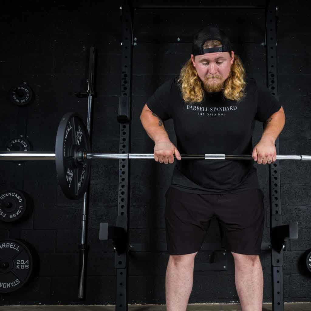 Man performing barbell rows with Barbell Standard Olympic barbell and weight plates in home gym