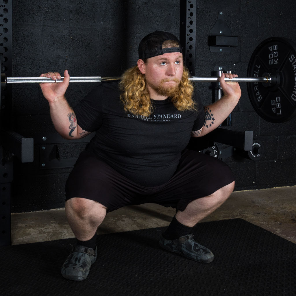 Man performing barbell squat with Barbell Standard Olympic barbell and weight plates in home gym