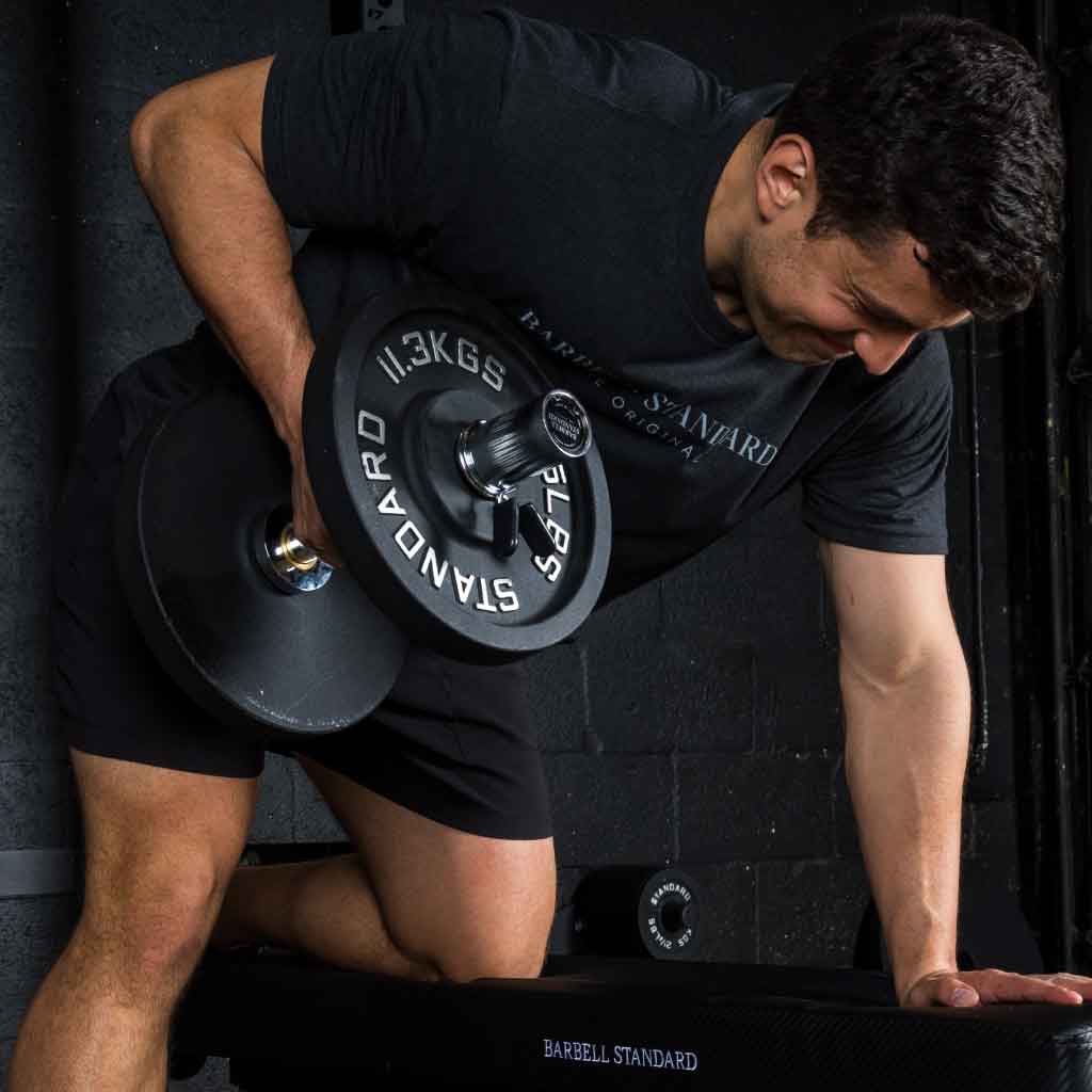 Barbell Standard 25 lb 11.3 kg iron weight plate loaded on dumbbell during single arm row exercise