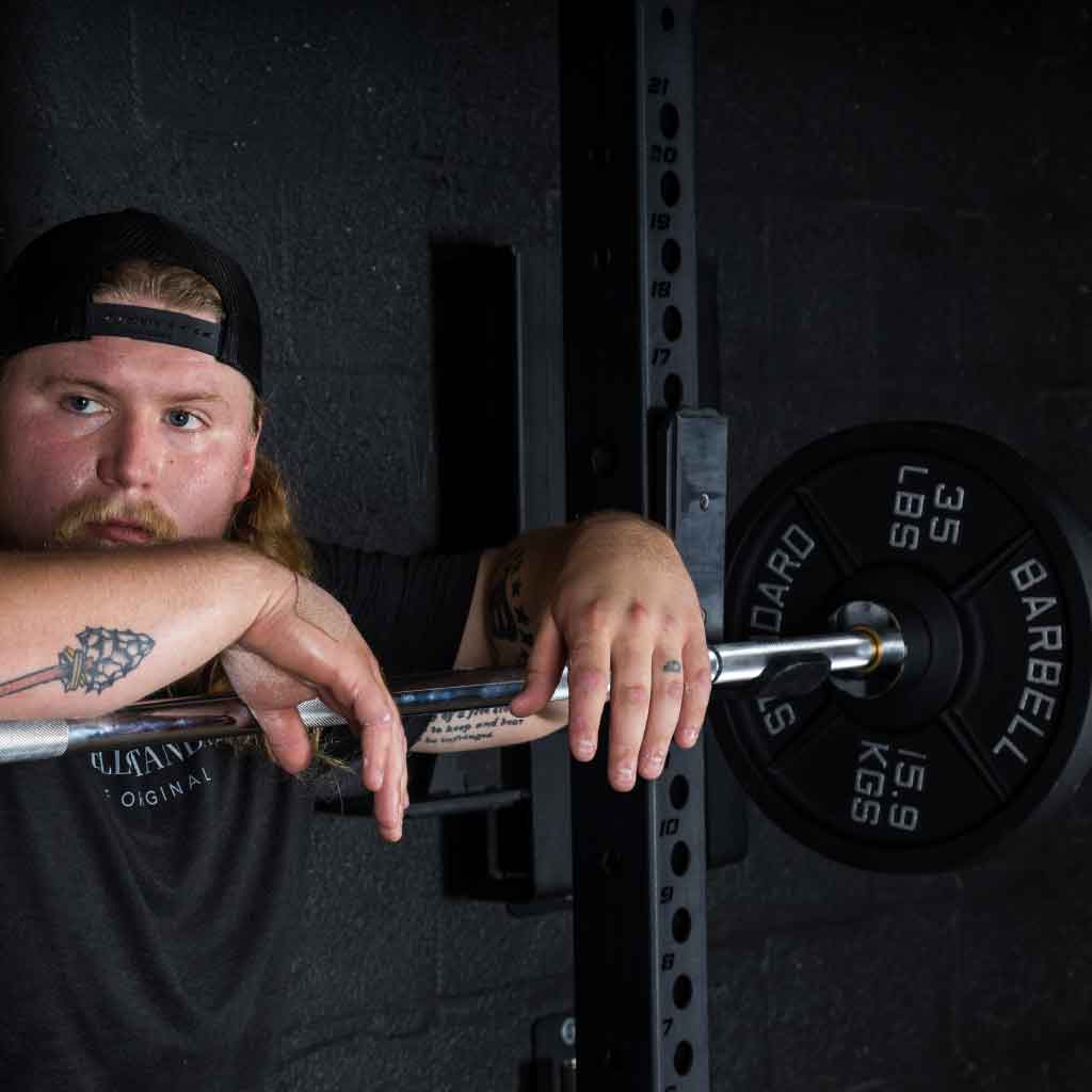 Barbell Standard 35 lb 15.9 kg iron weight plate on barbell with athlete resting in squat rack