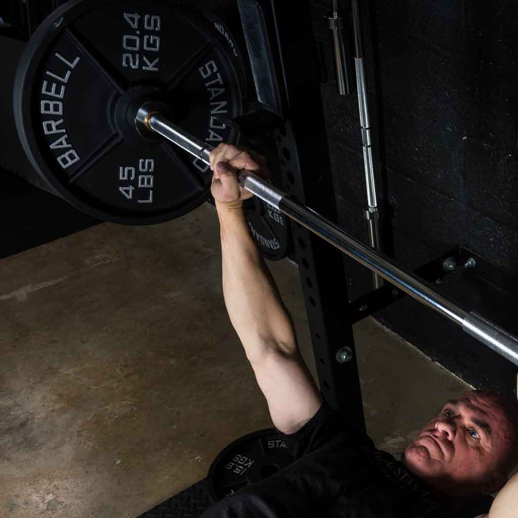 Barbell Standard 45 lb 20.4 kg iron weight plate loaded on barbell during bench press workout