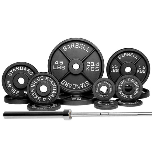 A variety of black free weights and a barbell with weight plates arranged in front of a white background.