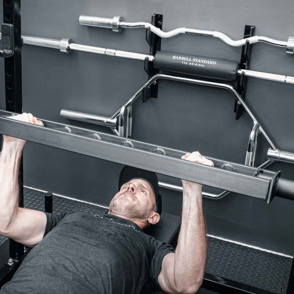 Athlete performing bench press with the Barbell Standard Swiss Multigrip Bar in a home gym