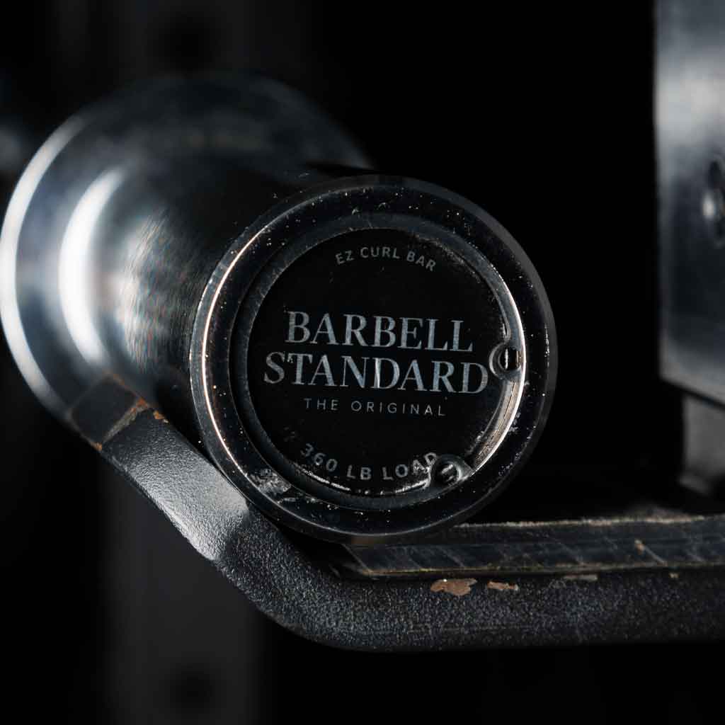 Barbell Standard EZ curl bar endcap with 350 lb load rating resting on gym rack