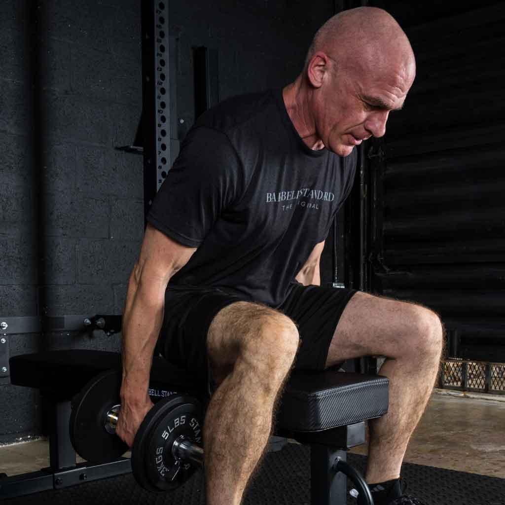 Man training with Barbell Standard adjustable dumbbell while seated on weight bench in gym