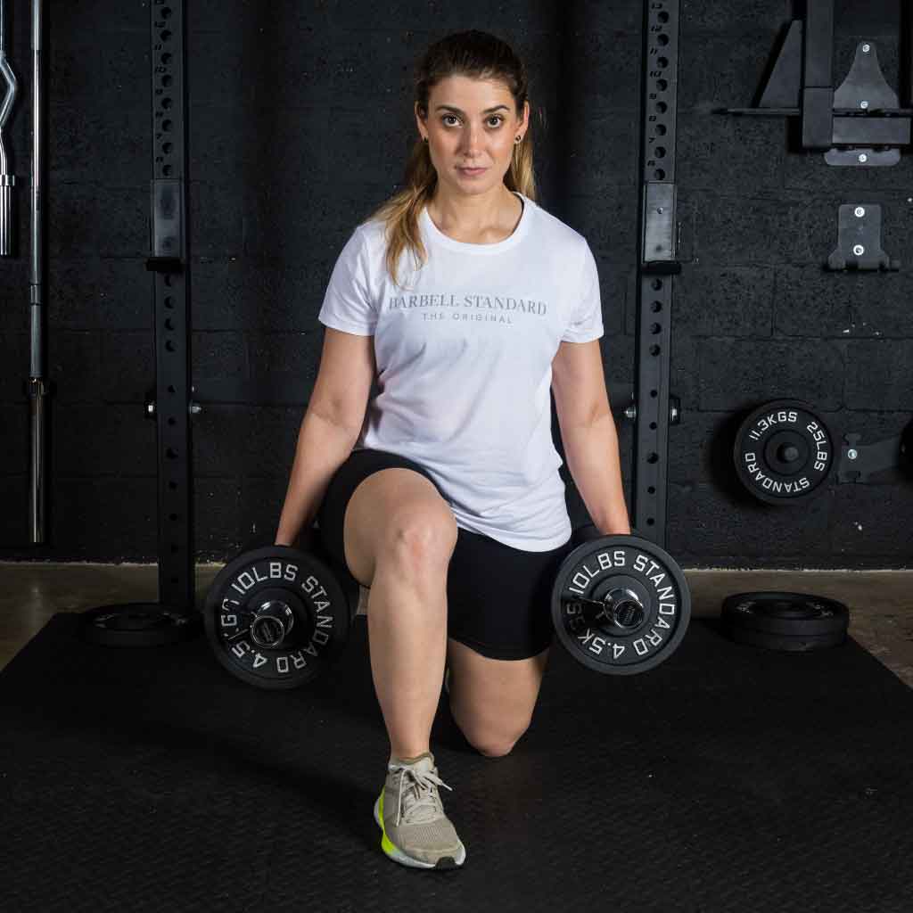 Woman performing lunge exercise with Barbell Standard adjustable dumbbells in a home gym setting