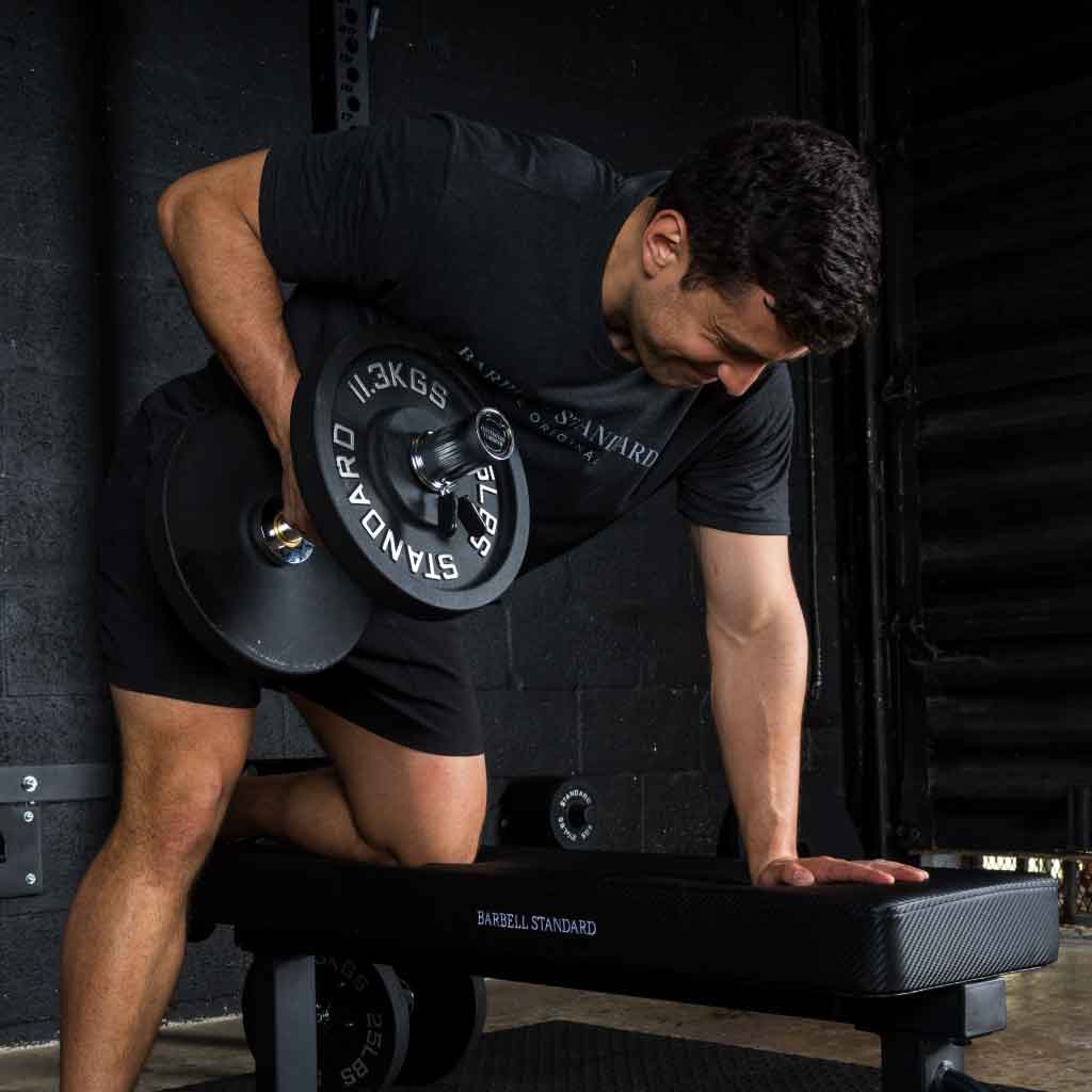 Man performing dumbbell row with Barbell Standard adjustable dumbbells on a flat weight bench
