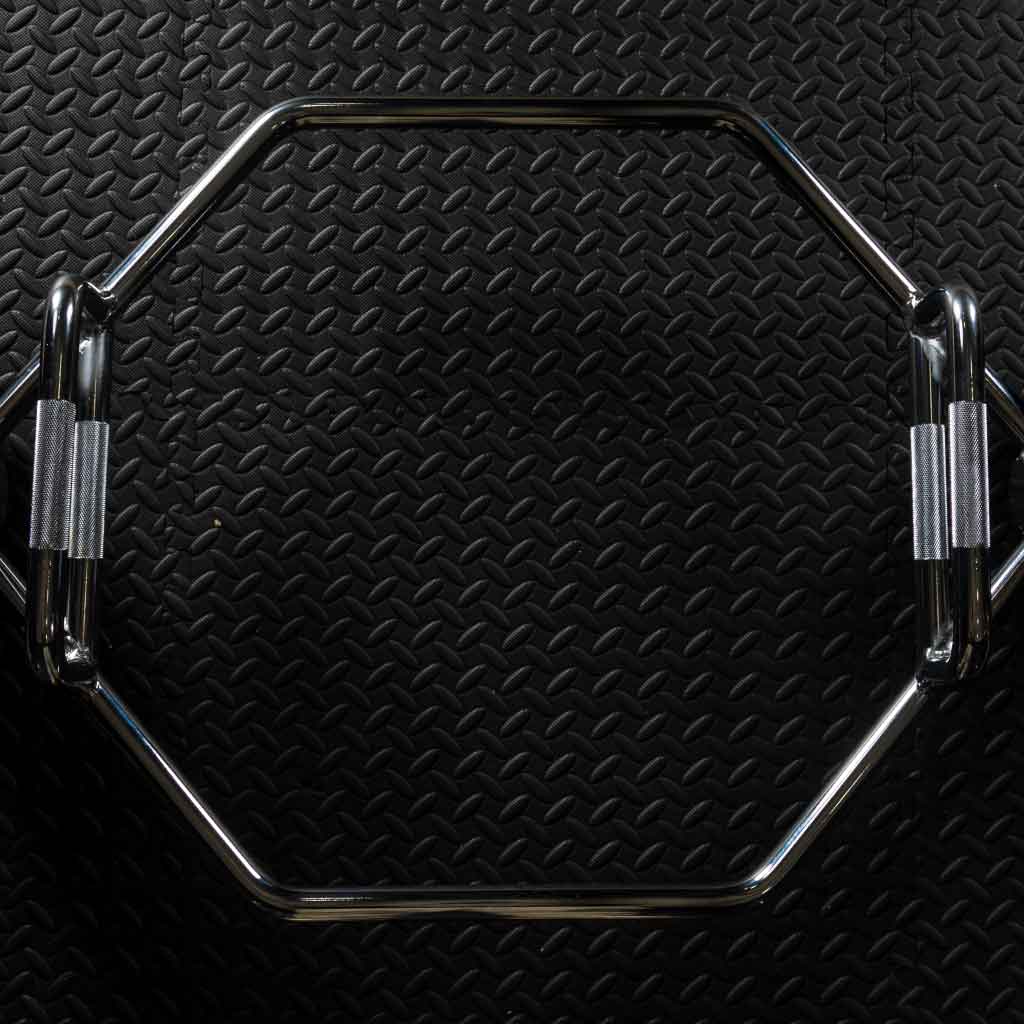 Barbell Standard hex trap bar with knurled handles photographed from above on textured gym flooring