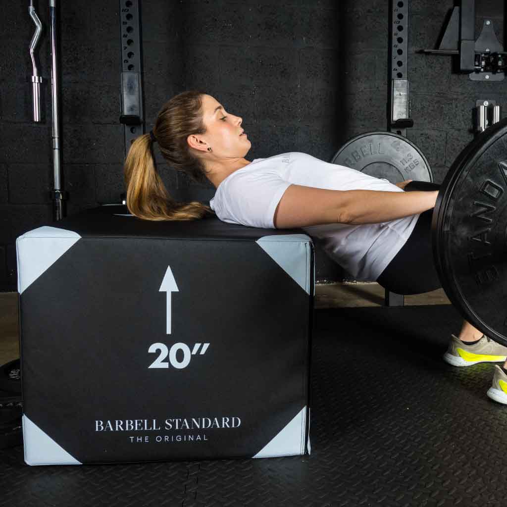 Woman performing barbell hip thrust on Barbell Standard 3-in-1 foam plyo jump box set at 20-inch height in gym