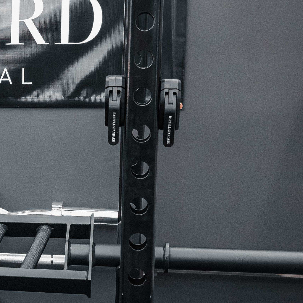 Pair of black Barbell Standard magnetic barbell collars attached to power rack upright in home gym