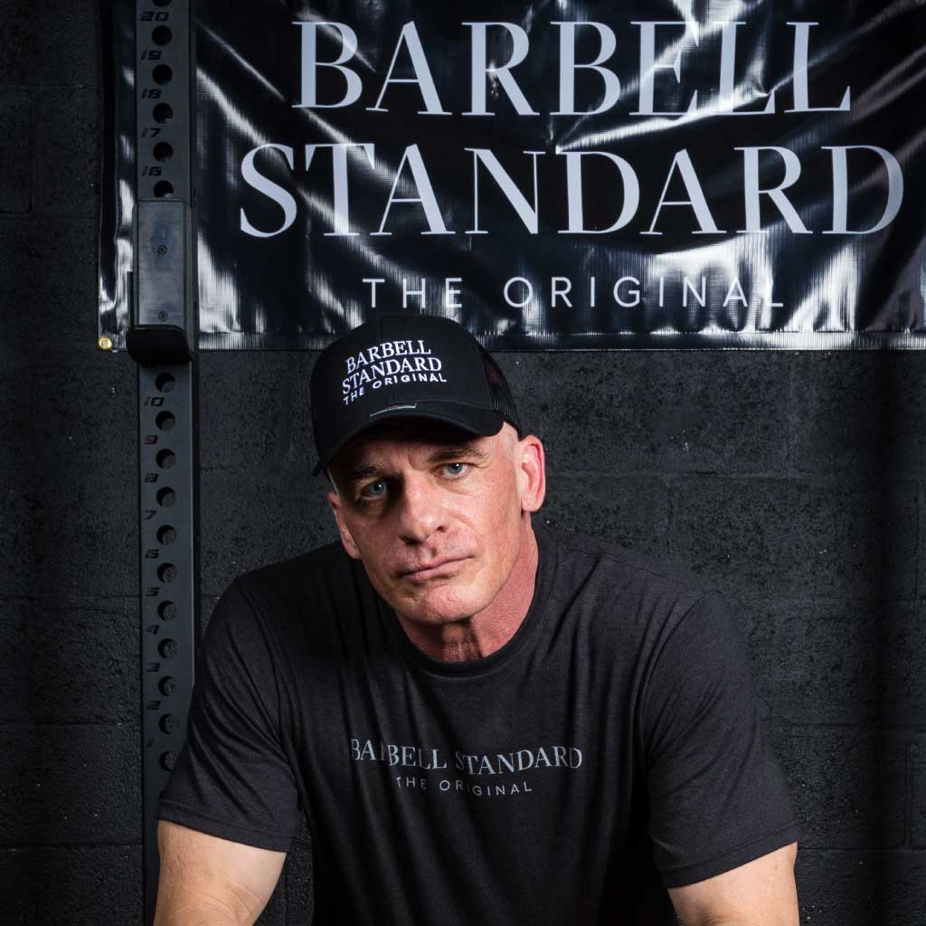 Man wearing black Barbell Standard trucker hat and t-shirt in gym setting