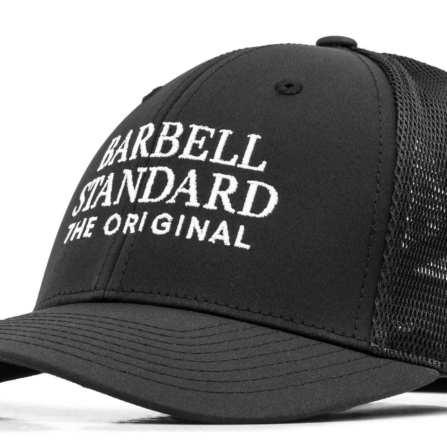 Close-up of black Barbell Standard trucker hat with white embroidered logo on front panel