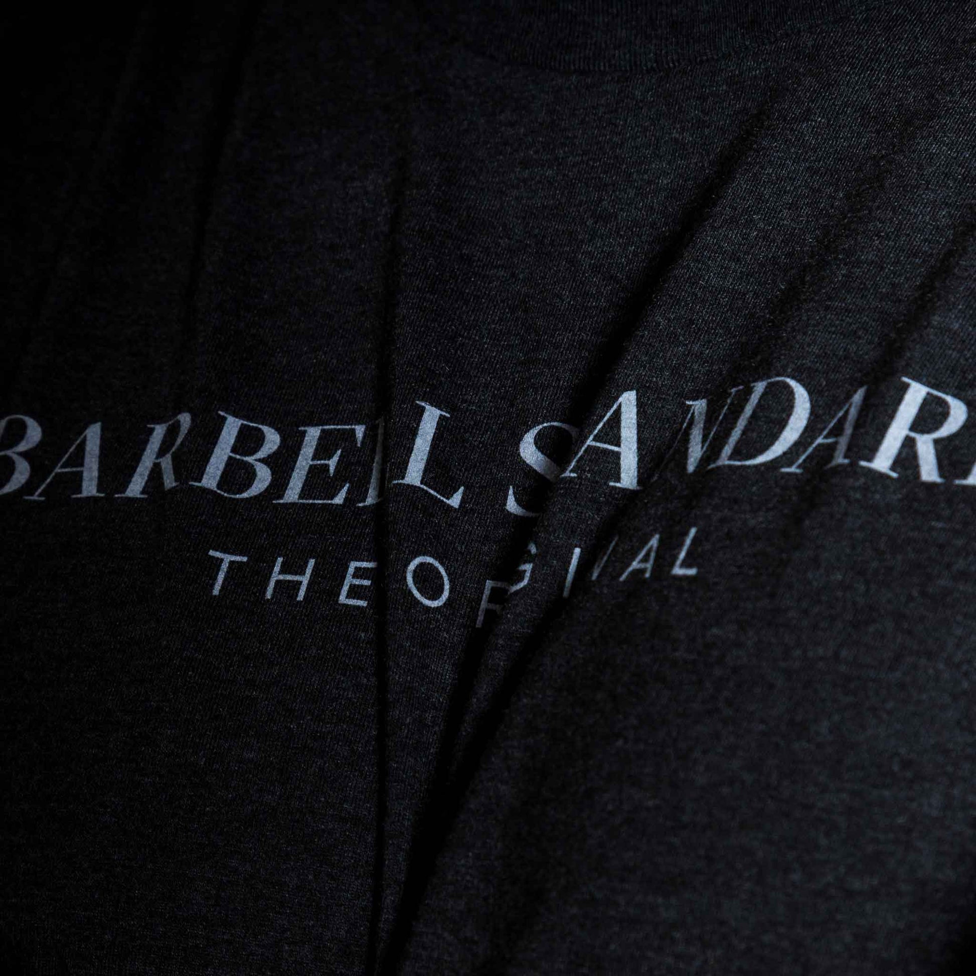Closeup of black Barbell Standard t-shirt with white "Barbell Standard The Original" logo text