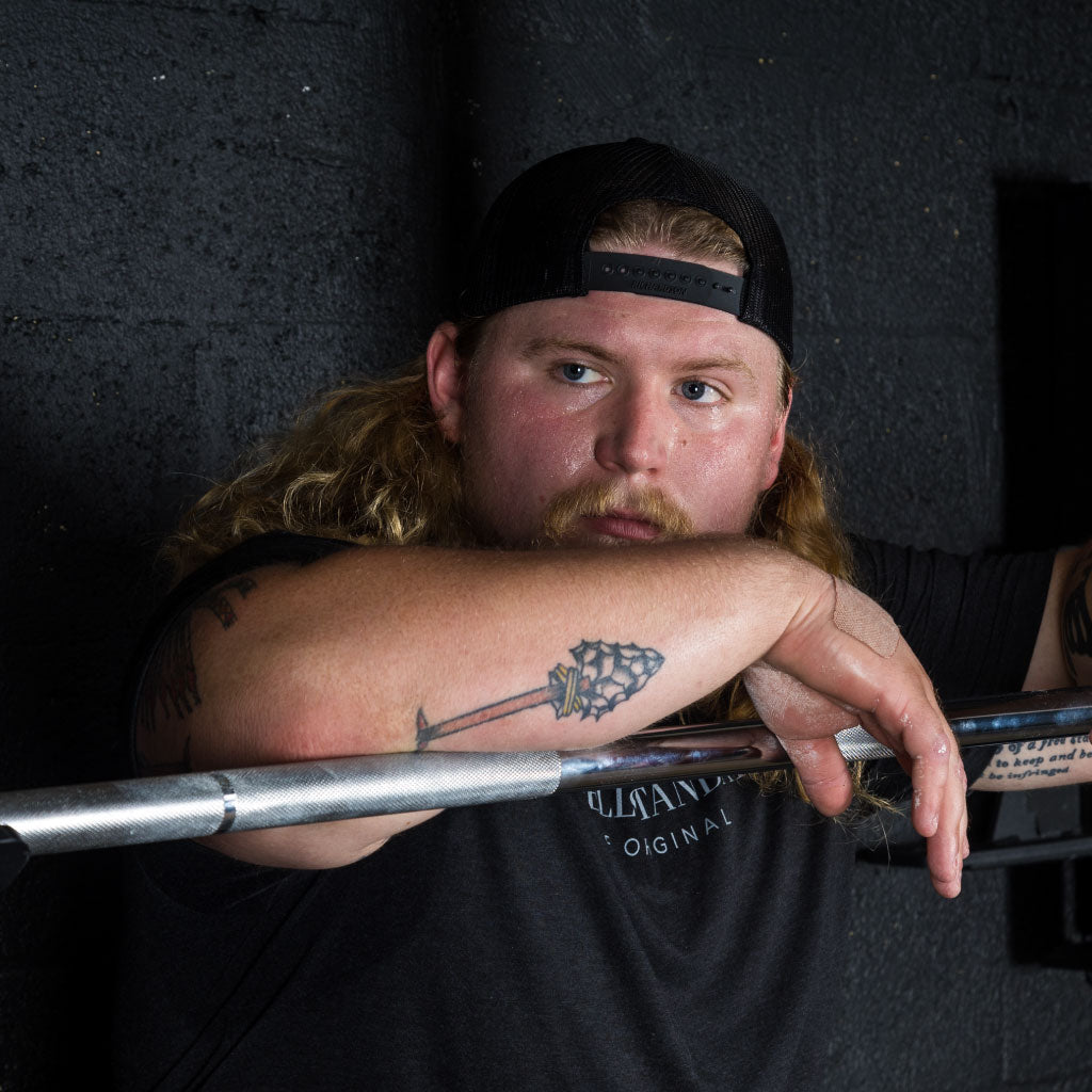 Parker rests on the Barbell Standard Olympic Bar, representing strength and grit in training.