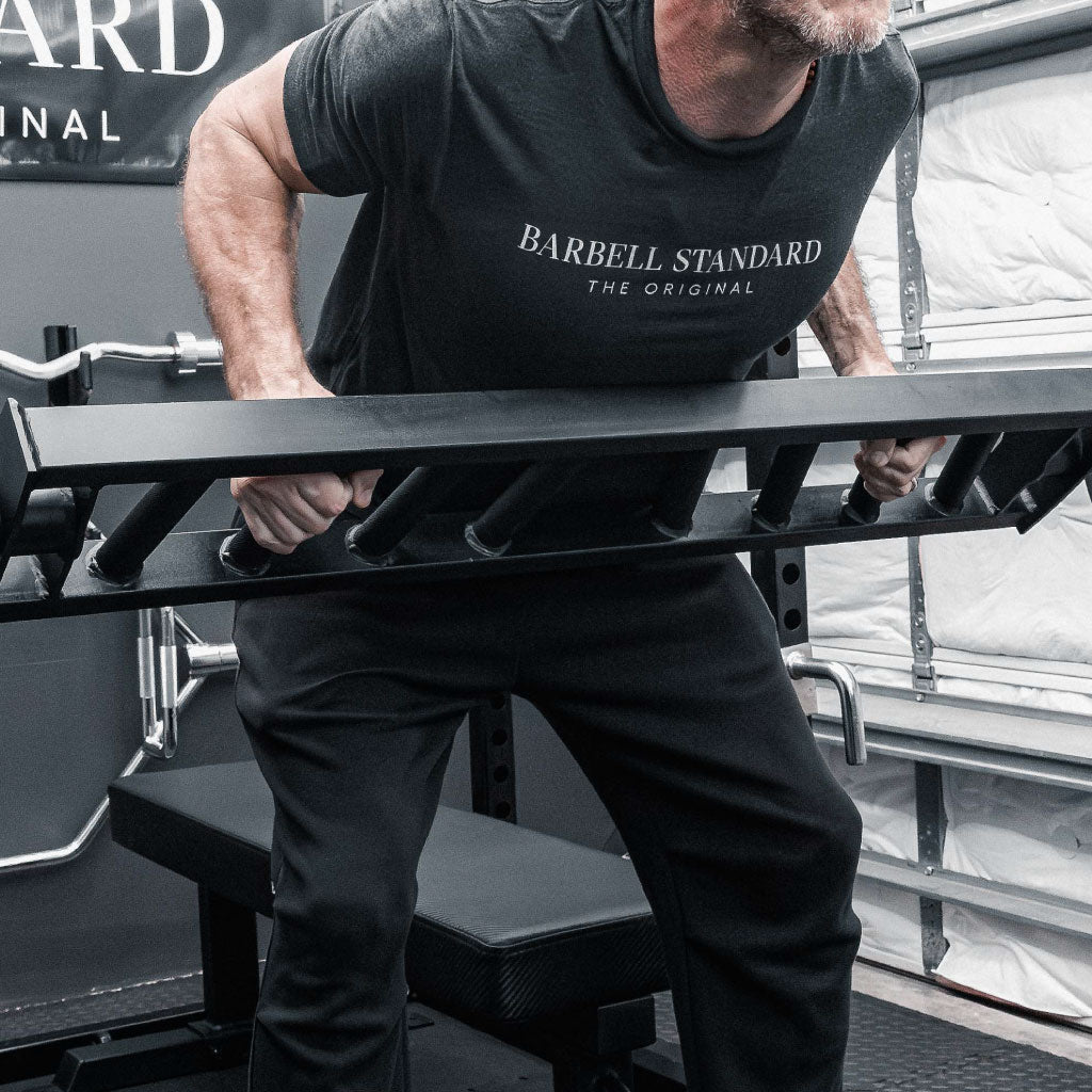 Man performing bent-over rows with Barbell Standard Swiss Multigrip Bar in a home gym
