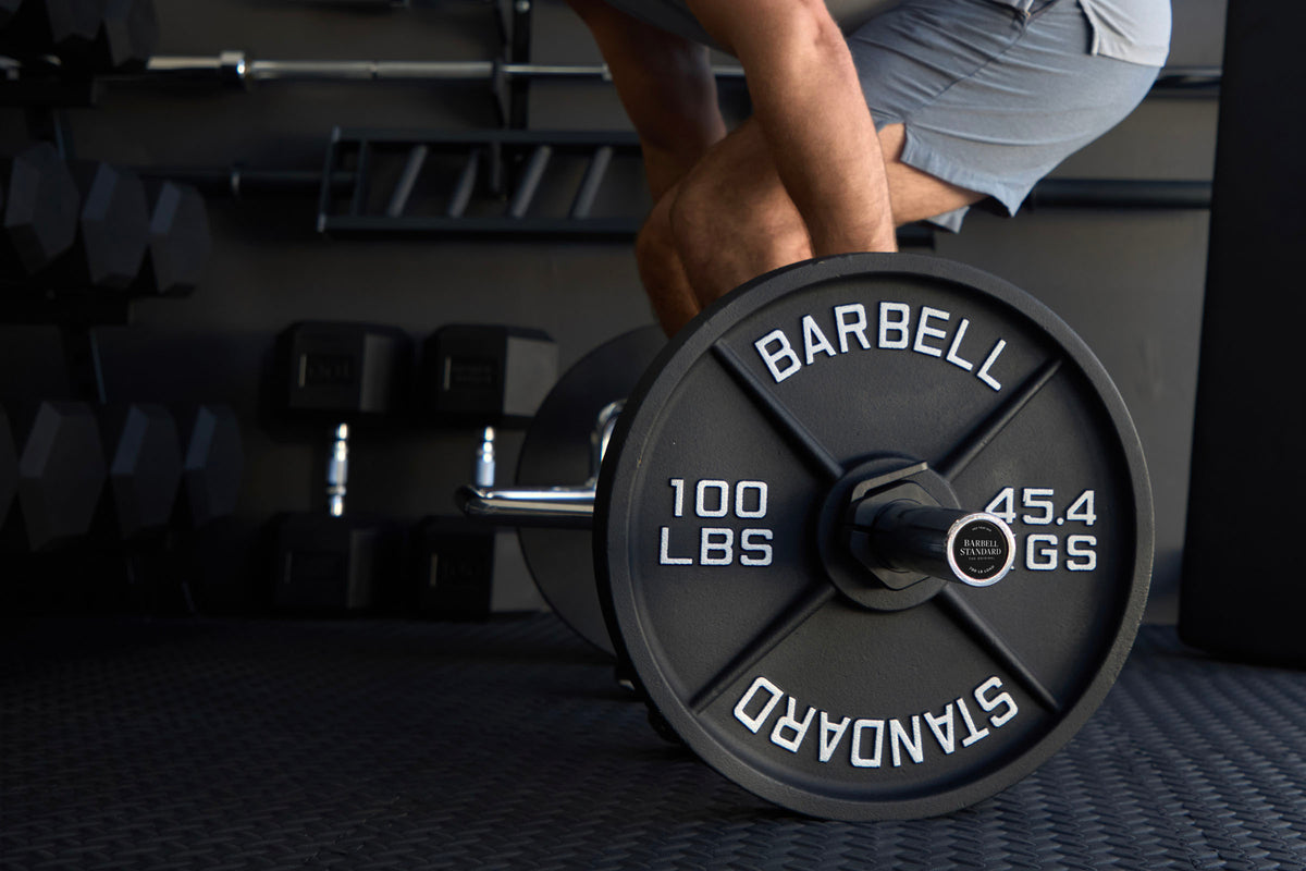 Lifter setting up a deadlift with a Barbell Standard 100 lb iron plate on the bar