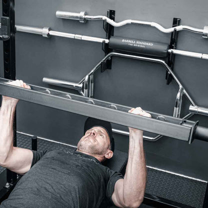 Athlete performing bench press with the Barbell Standard Swiss Multigrip Bar in a home gym