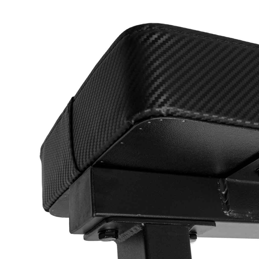 Close-up of Barbell Standard competition flat bench underside showing carbon fiber pad, reinforced stitching, and steel frame